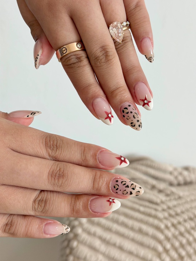 Nude almond nails with tiny red stars and leopard spots