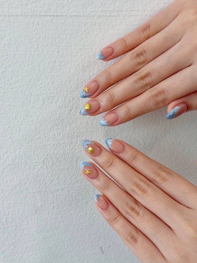 Nude nails with blue tips and gold accents